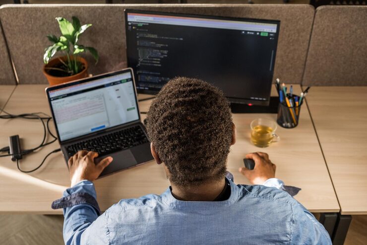 man writing lines of code desktop