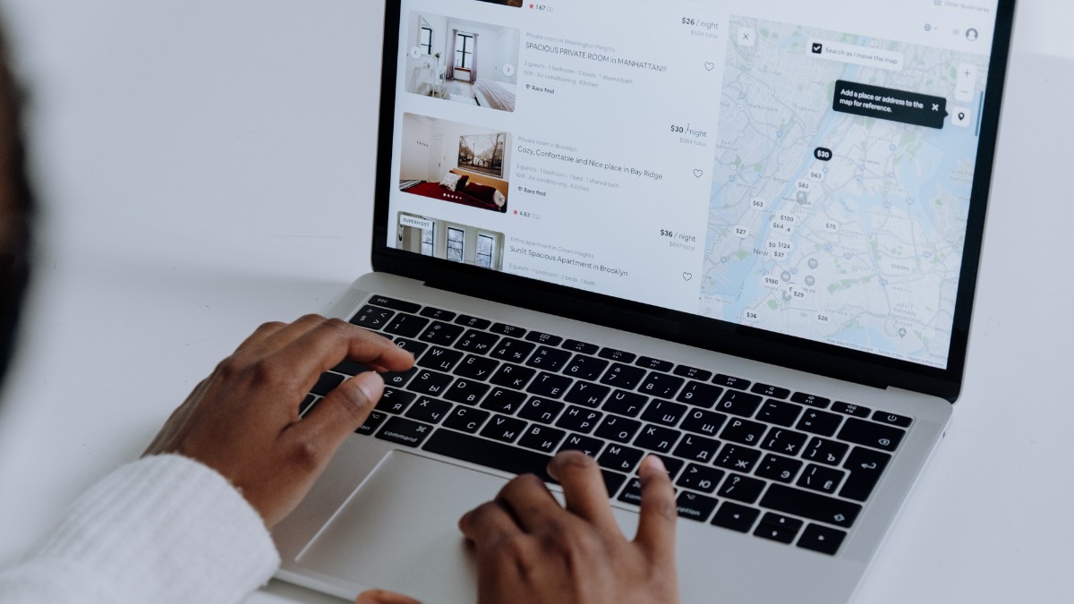 using a laptop to browse vacation rental listings alongside a digital map view